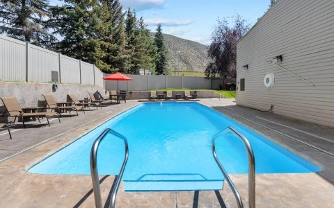 a pool with a red umbrella and chairs
