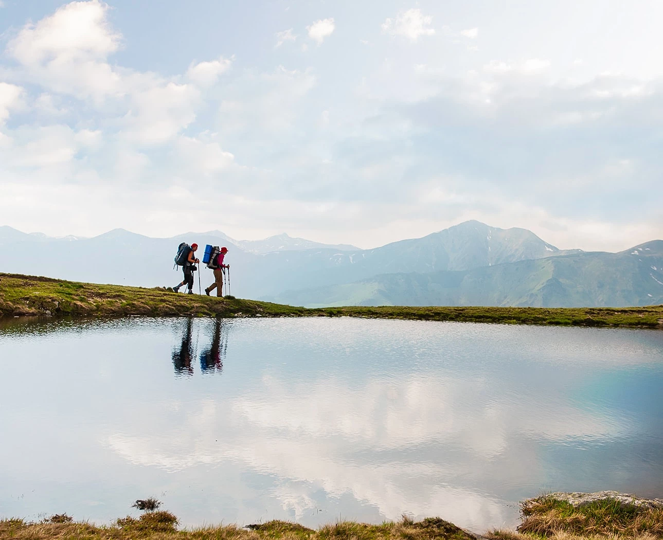 a couple of people standing on a hill by a body of water