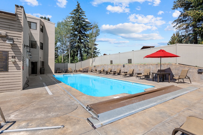 a pool with chairs and a red umbrella