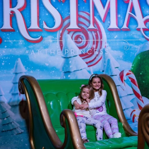 two girls sitting on a green sleigh