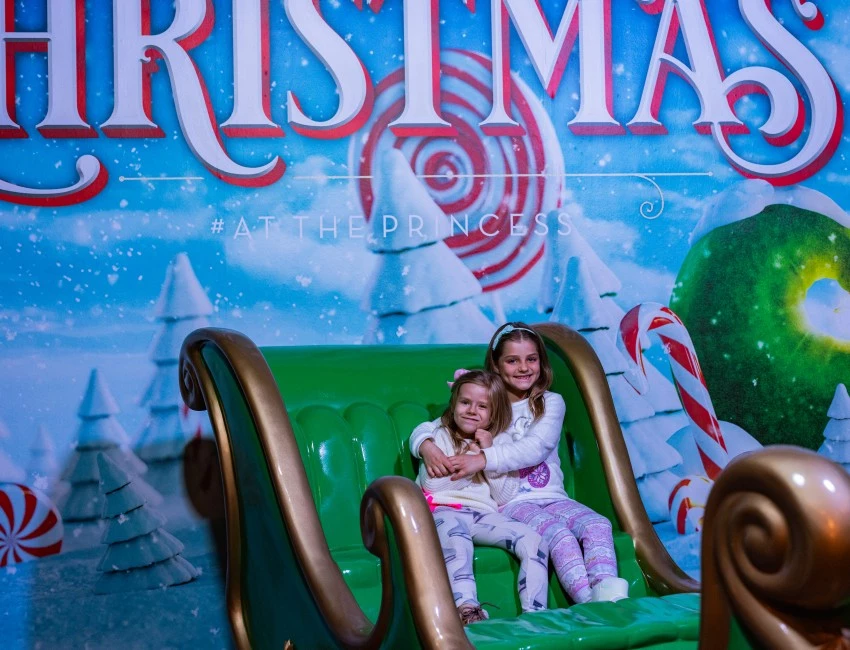 two girls sitting on a green sleigh