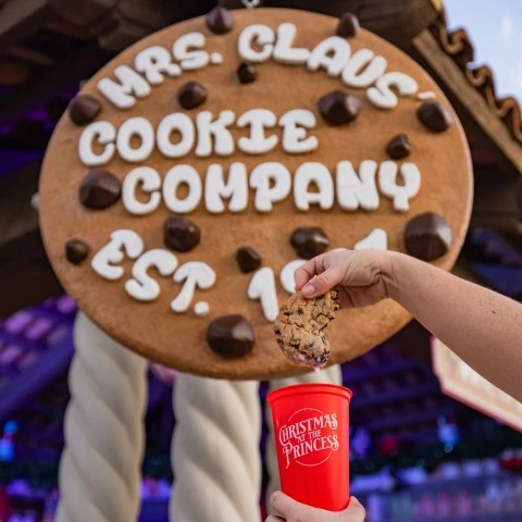 a hand holding a cookie and a cup