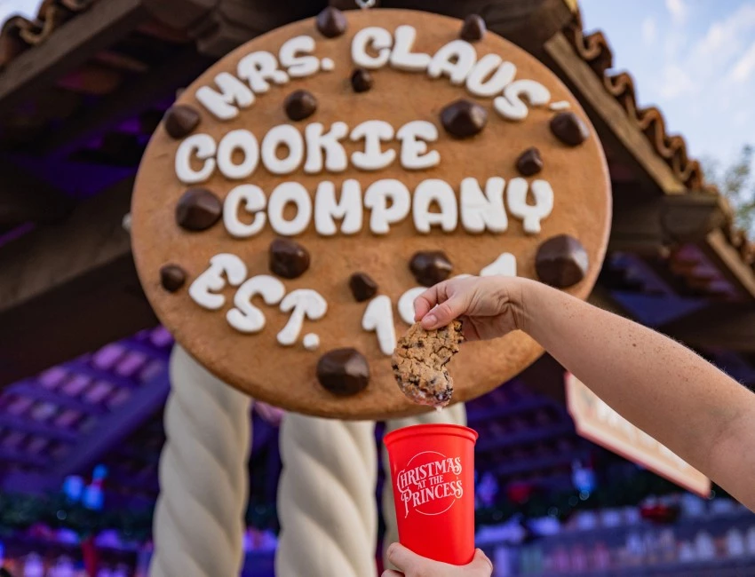 a hand holding a cookie and a cup