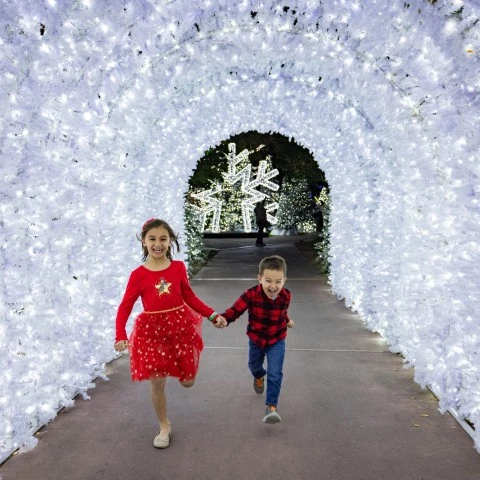 two children running in a tunnel of lights