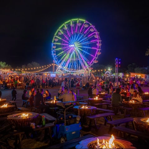 a ferris wheel with many tables and chairs at night smores land  