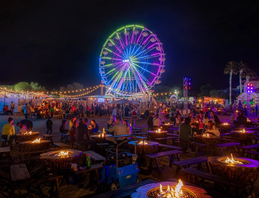a ferris wheel with many tables and chairs at night smores land