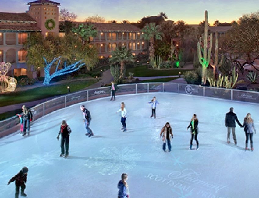 an outdoor ice skating rink with people on it at sunset
