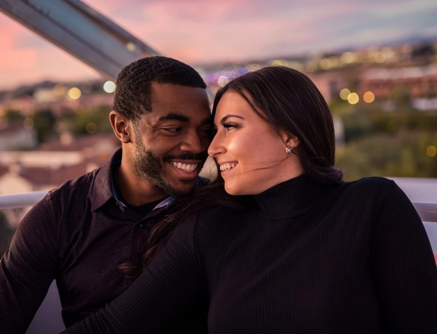 a smiling couple looking at each other at sunset