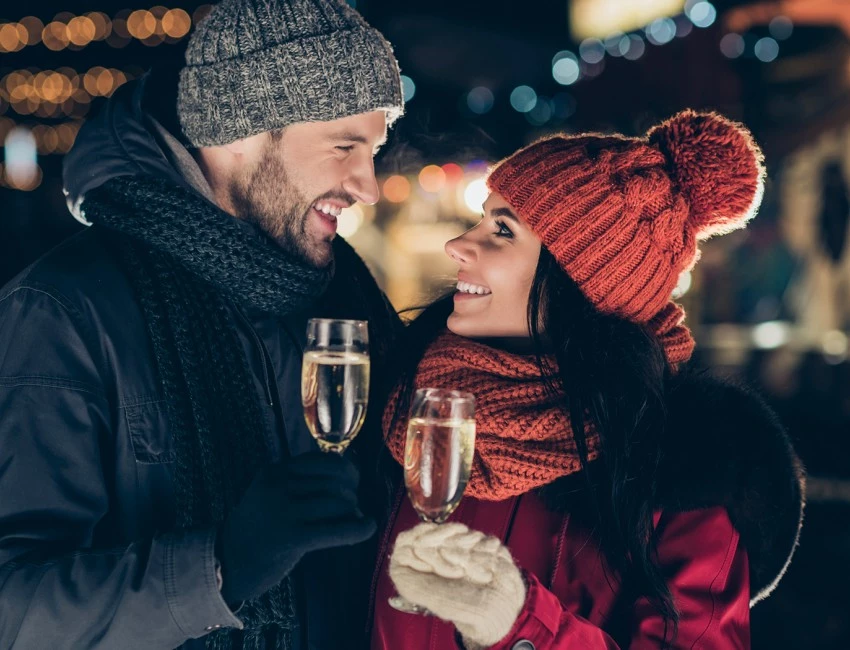 a smiling couple looking at each other while standing outside