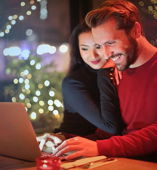 a man looking at his laptop while a girl is smiling next to him