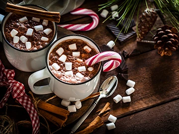two mugs of hot cocoa with marshmallows and candy canes