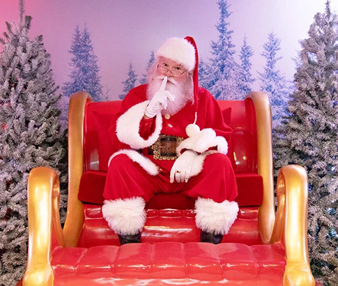 santa sitting in his sleigh with his hand over his mouth