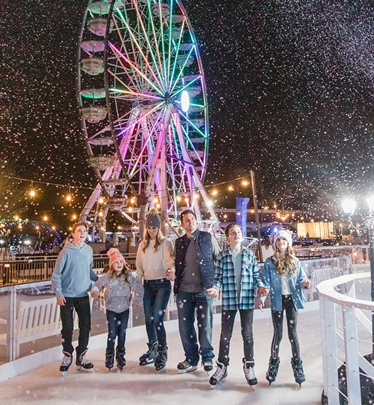 a family of six ice skating while its snowing outside smores land