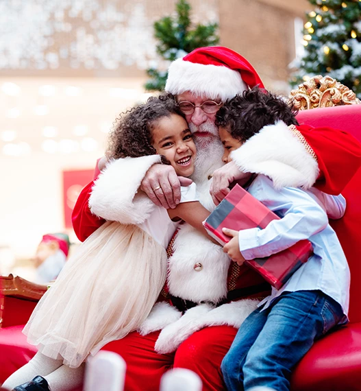 santa hugging two young kids