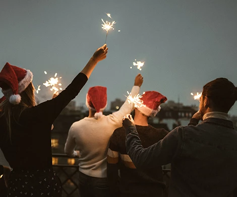 a group of people wearing santa hats holding sparklers