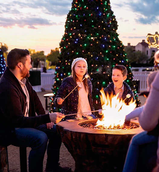 a group of people sitting around a table with a tree and a building in the background