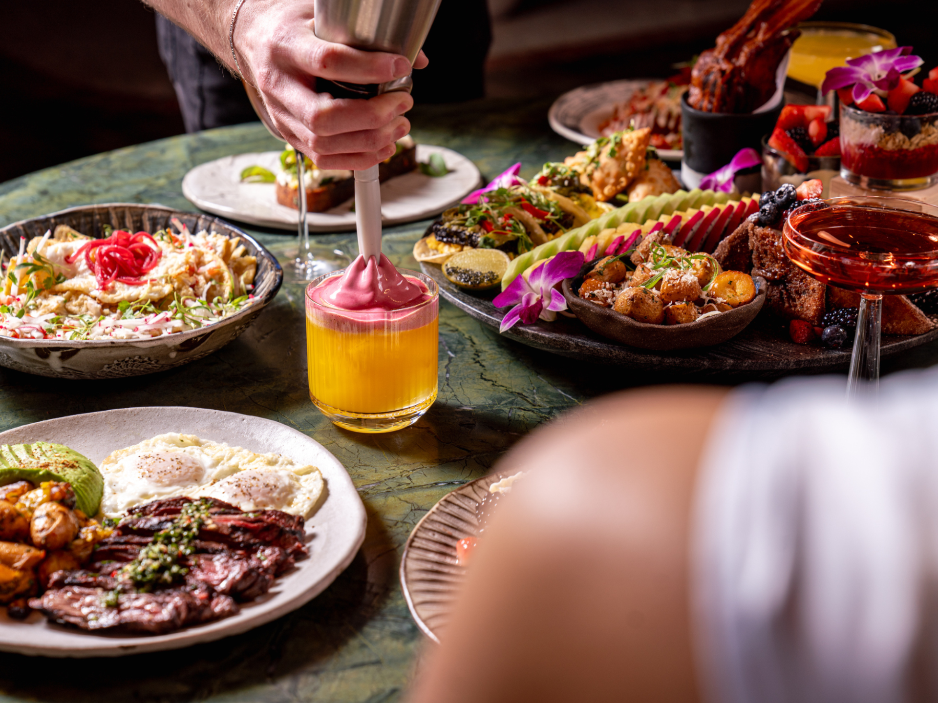 a person holding a blender over a table full of food