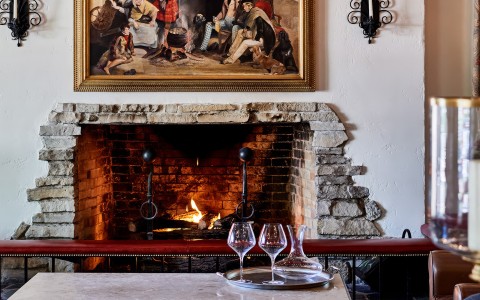 a fireplace with wine glasses on a table main