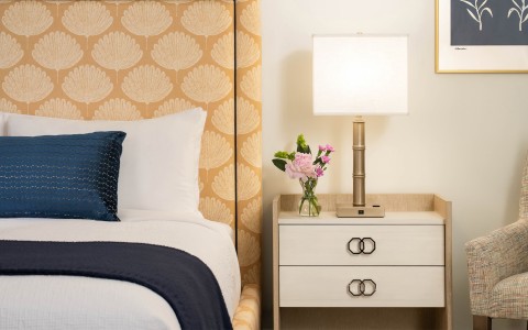 a bed with a lamp and flowers on a nightstand main