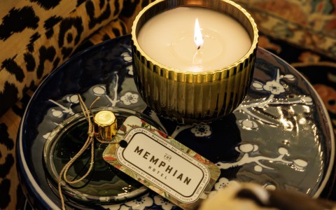a candle in a gold bowl with a label on a blue plate main