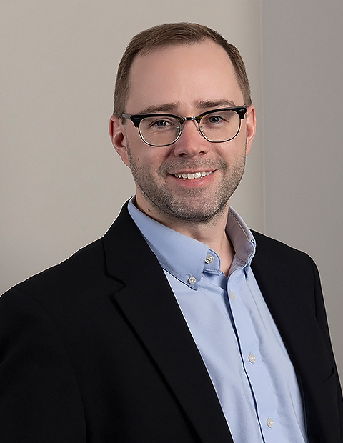 a man wearing glasses and a suit image of Derek Fisk