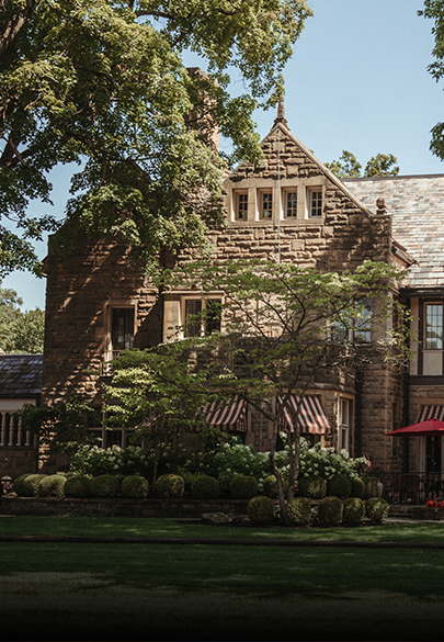 a large brick house with trees and a lawn