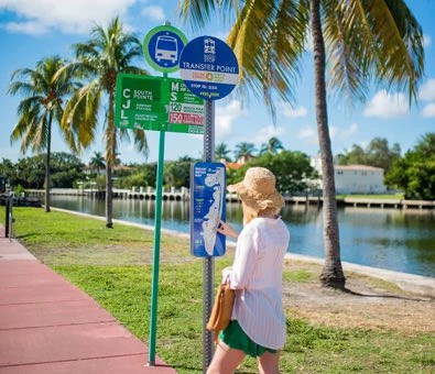 young blonde woman in shorts and a blouse standing at the bus stop