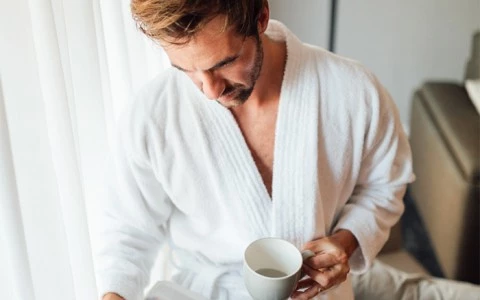man holding a cup of coffee with a newspaper