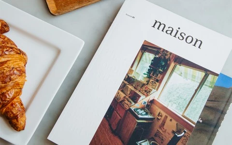top view of a table with magazines and plates with a croissant and a coffee