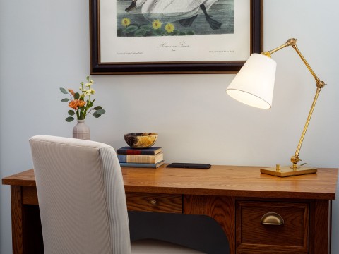 a desk with a lamp and a picture on the wall