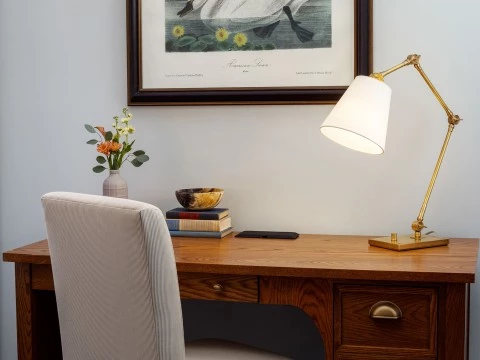 a desk with a lamp and a picture on the wall