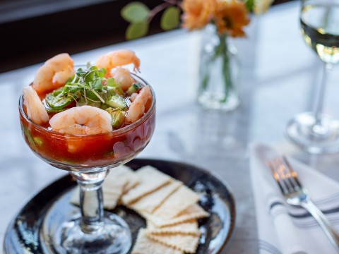 a glass of shrimp cocktail with crackers on a plate