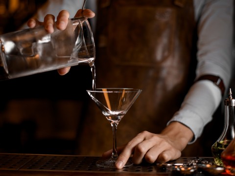 a person pouring liquid into a martini glass