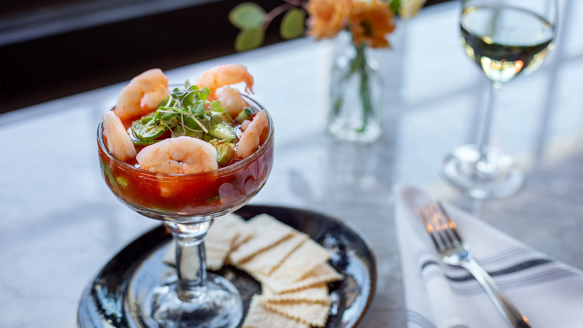 a glass of shrimp cocktail with crackers on a plate