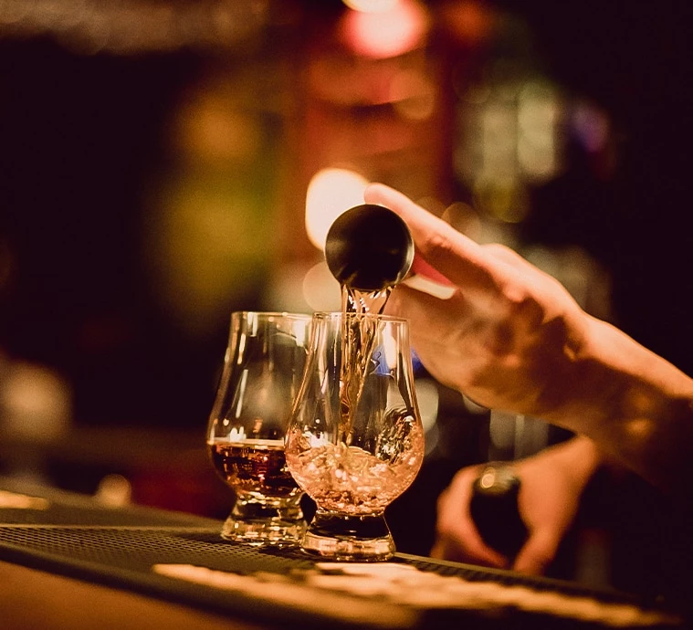 a person pouring a drink into a glass