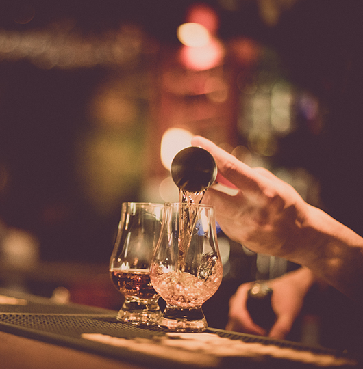 a person pouring alcohol into a glass