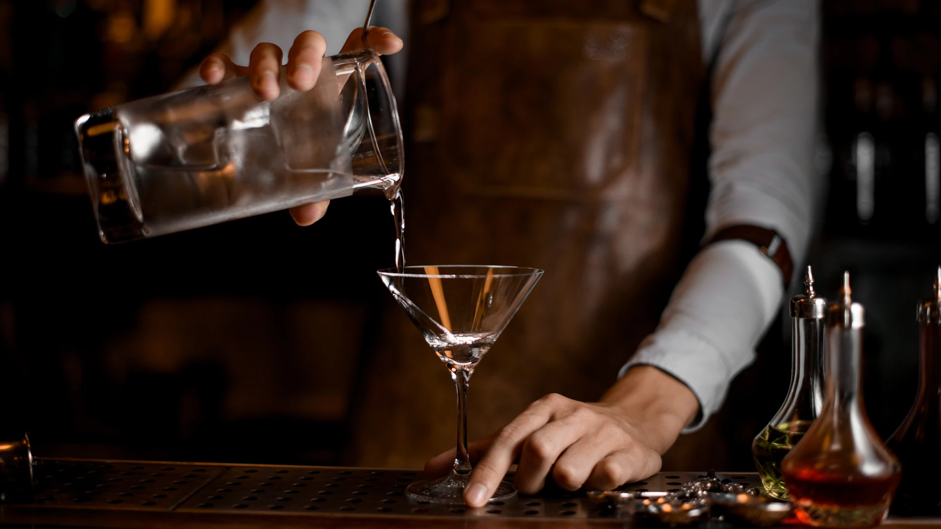 a person pouring liquid into a martini glass