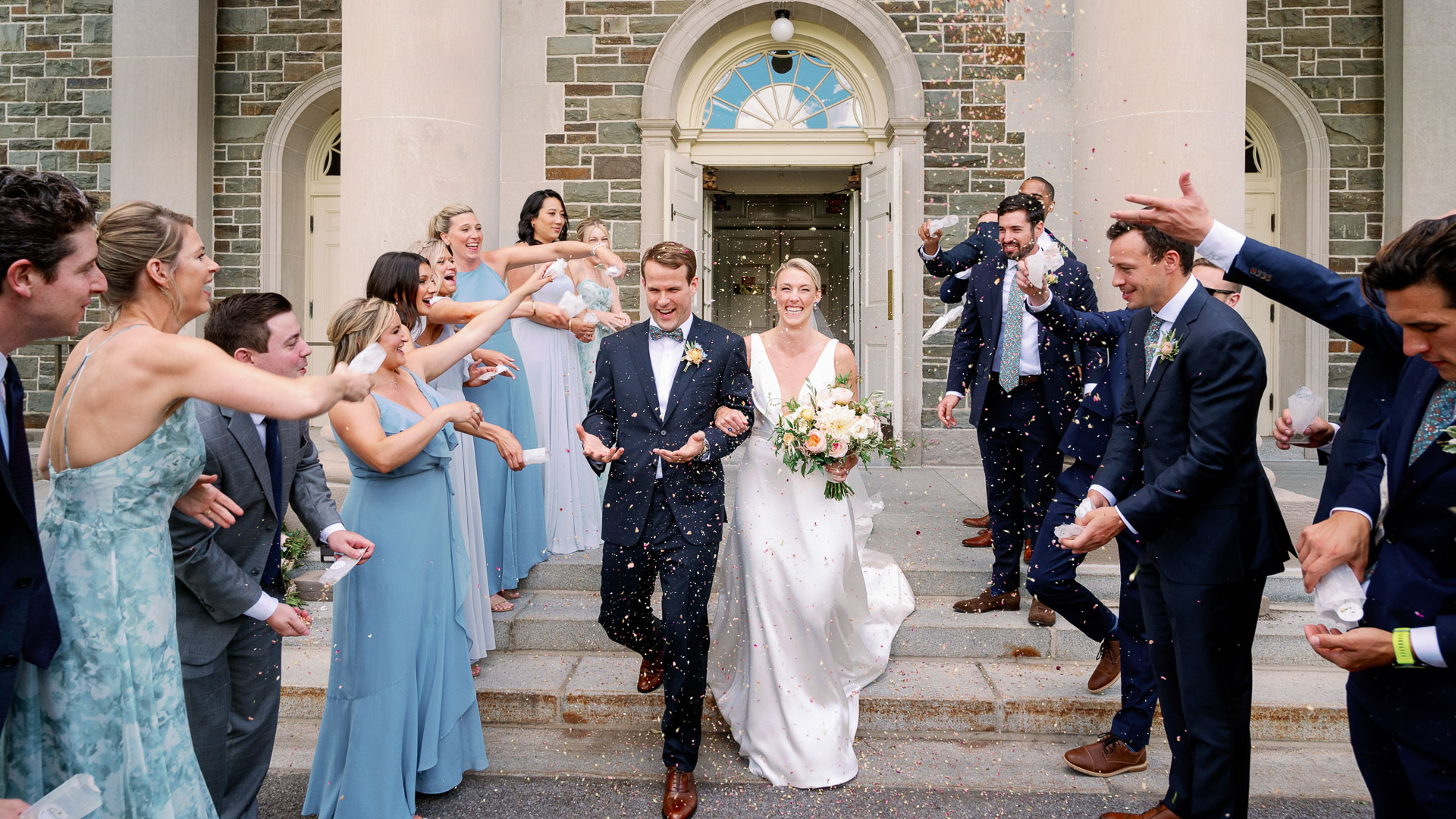 a group of people throwing confetti to a bride and groom