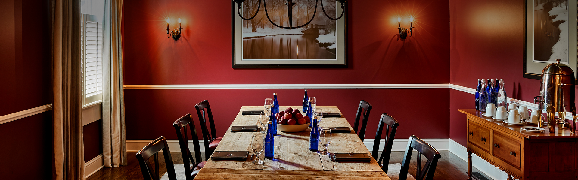 a table with a bowl of fruit and blue bottles on it