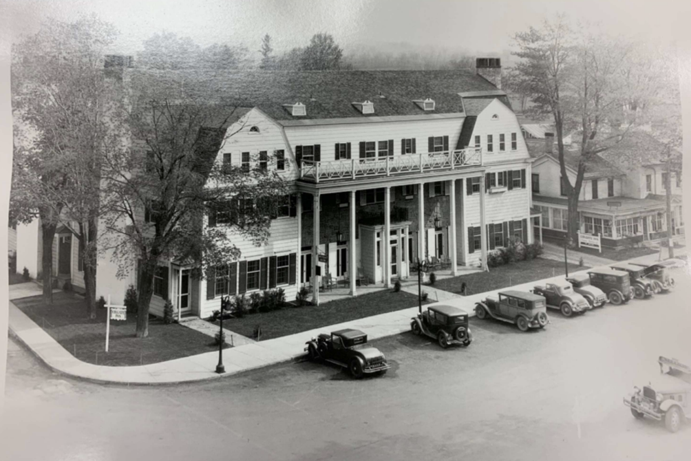 a black and white photo of a building with cars parked in front