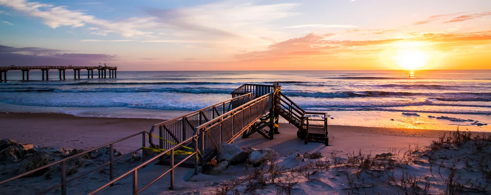 a beach with a pier and a sunset