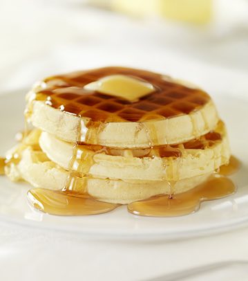 Stack of pancakes, juice & bowl of strawberries on table
