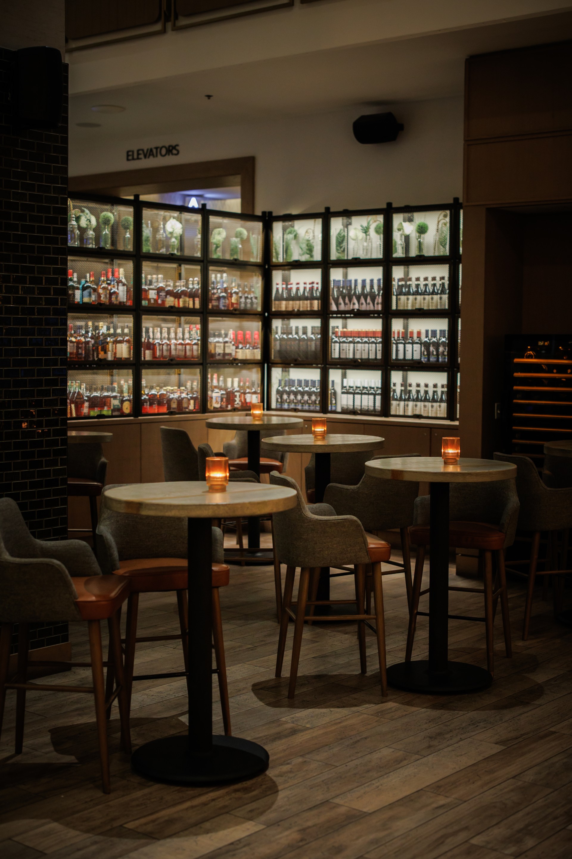 a room with tables and chairs and a display of bottles