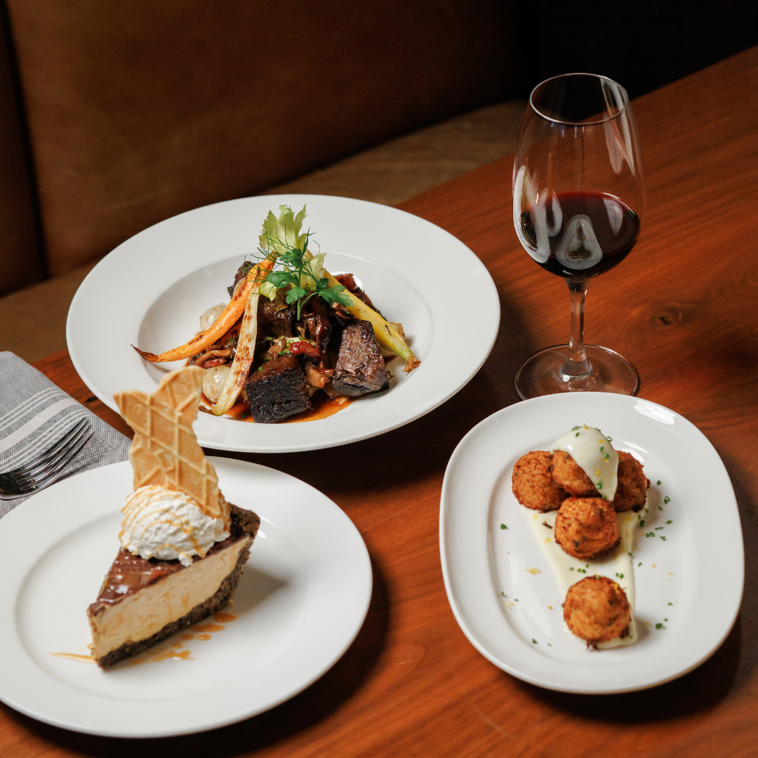a table with plates of food and a glass of wine
