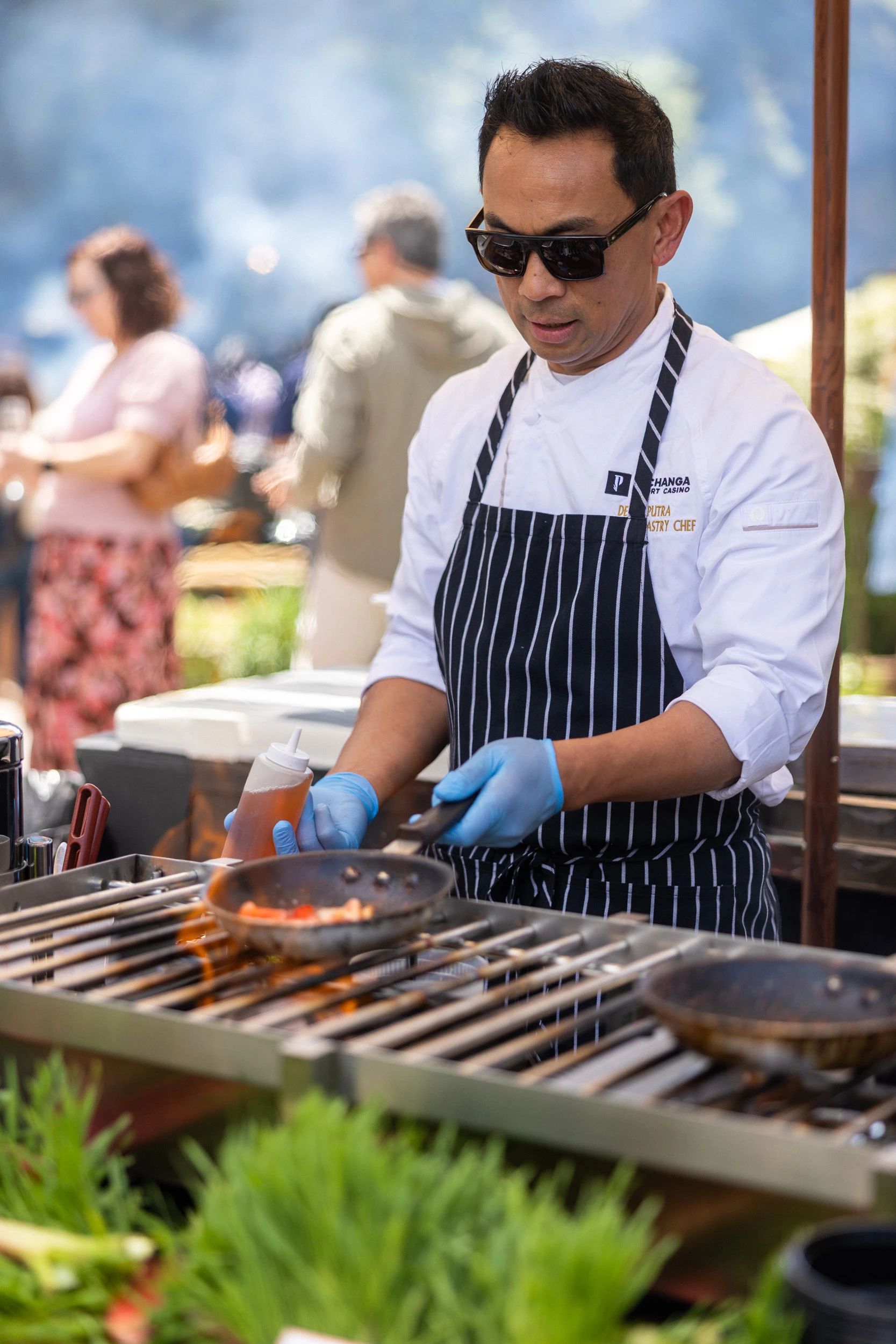 a man wearing sunglasses and a black and white apron cooking food