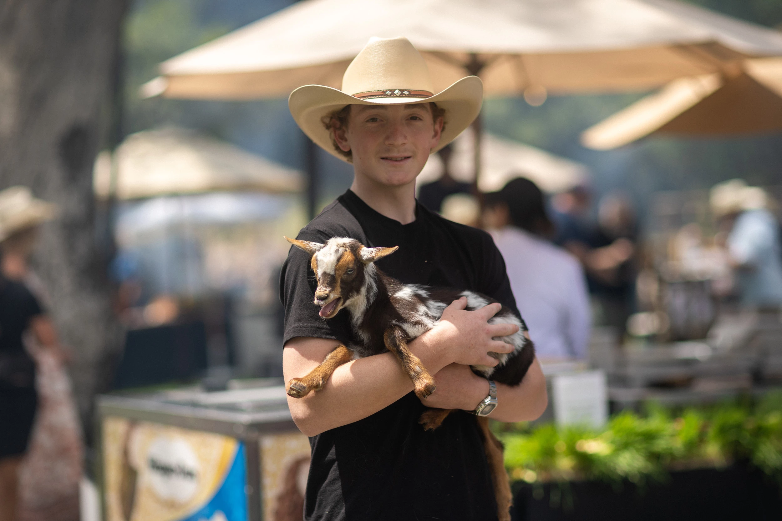 a man in a cowboy hat holding a goat