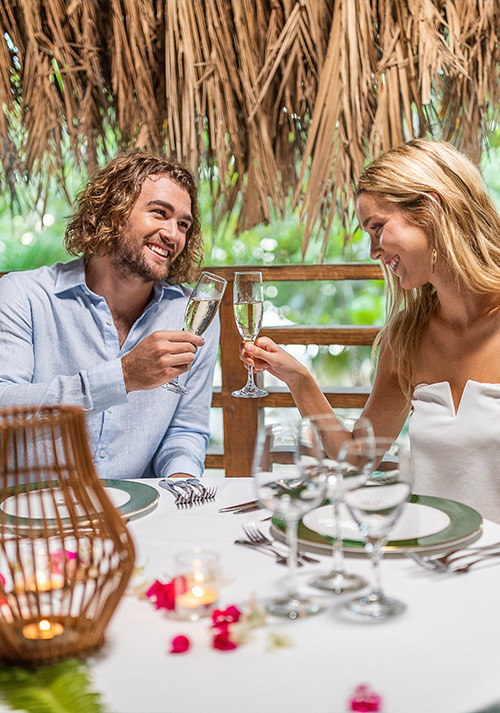 a man and woman sitting at a table with glasses of champagne