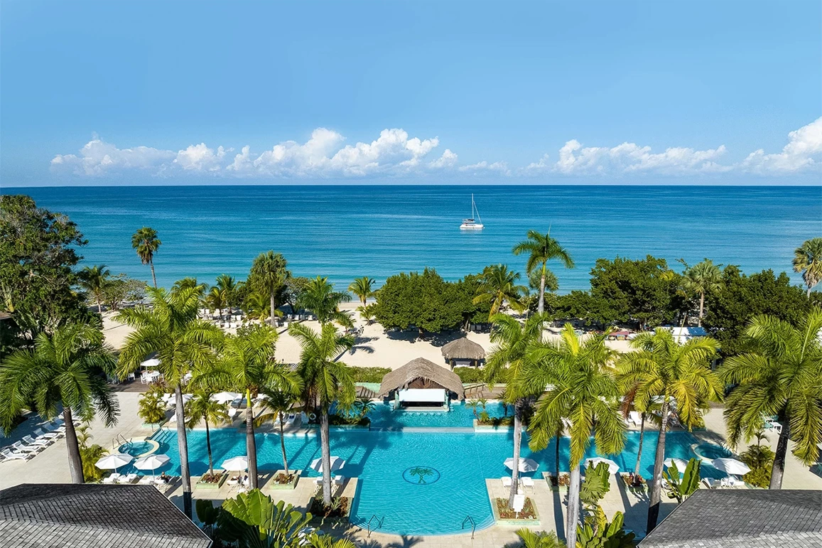 a swimming pool with palm trees and a boat in the background