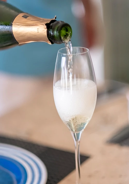 a person pouring champagne into a glass