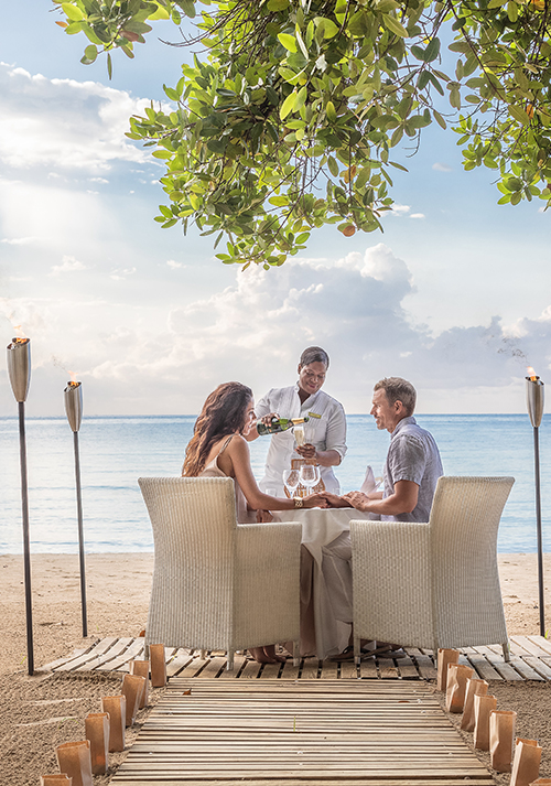 a group of people sitting at a table with wine glasses on a beach